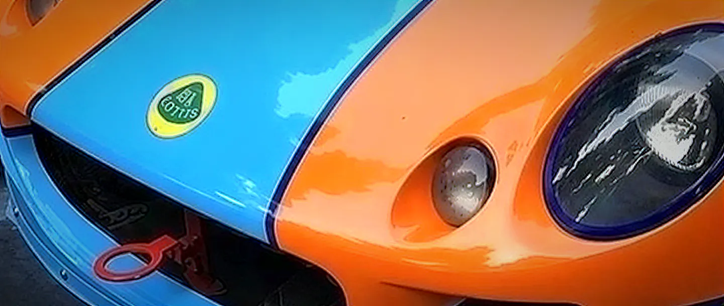 Detail přídě: odznak Lotus na modrém pruhu, světlomet a přední splitter