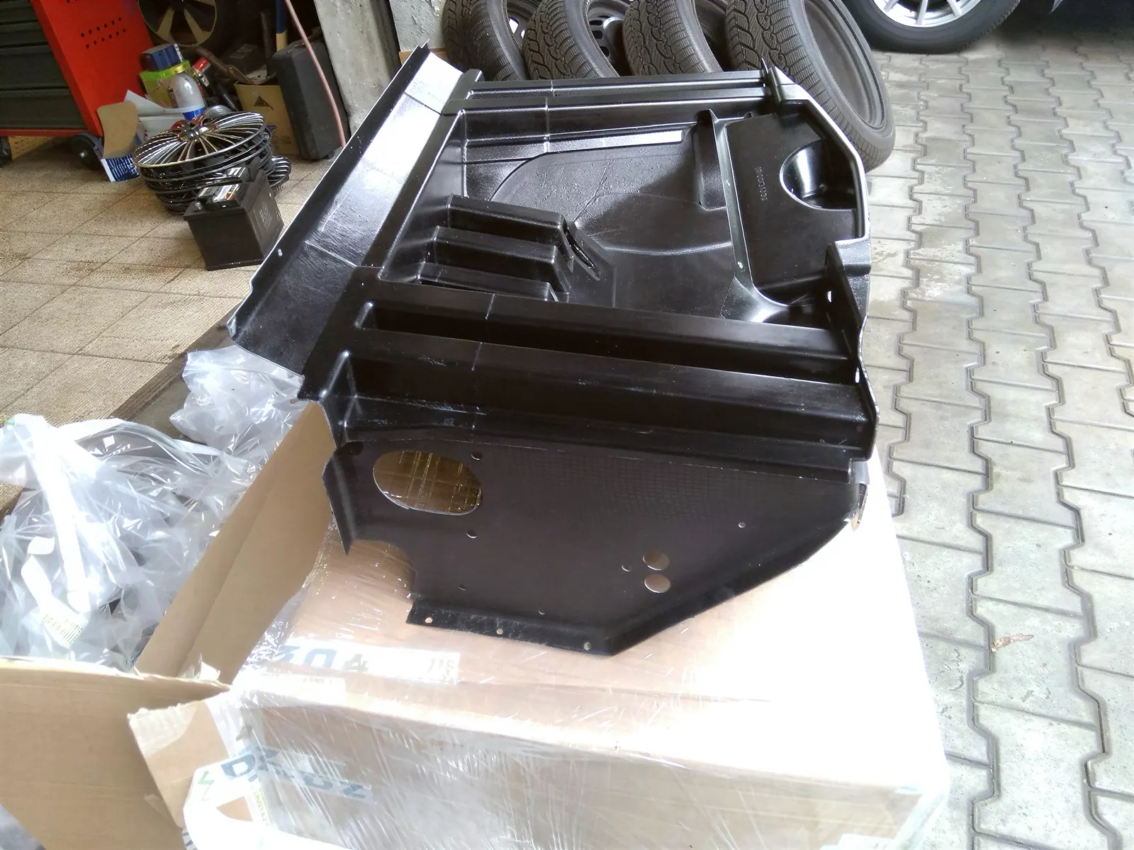 Černý kompozitový crash box Lotusu na paletě před dílnou